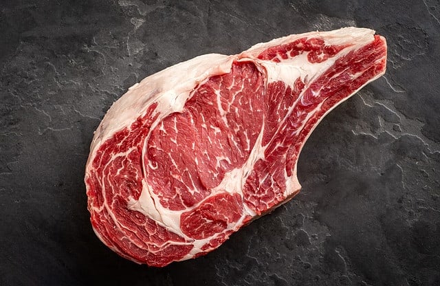 raw cowboy steak on stone background, prime rib eye on bone, top view