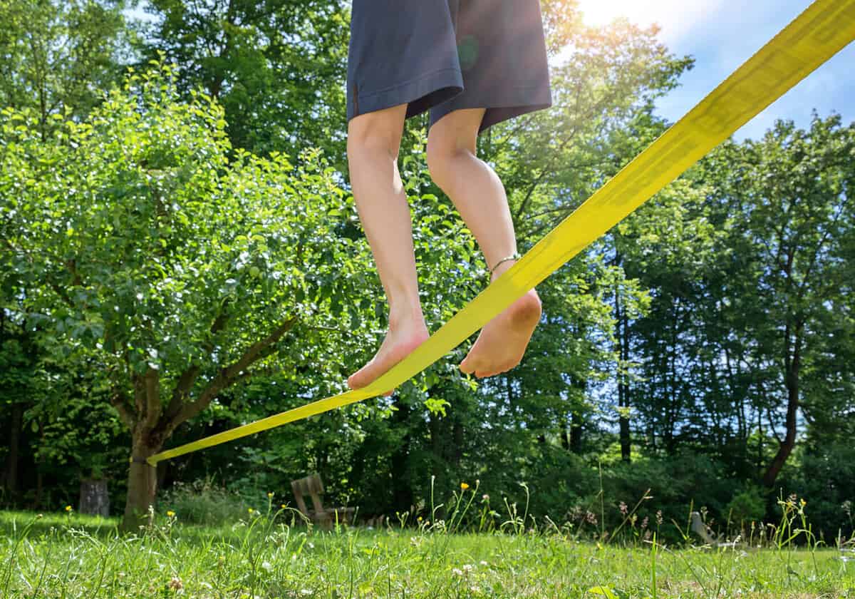 Kid balancing barefooted on a slack line, close up in low angle view