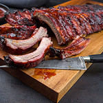 Barbecue pork spare ribs St Louis cut with hot honey chili marinade as closeup on an modern design wooden cutting board
