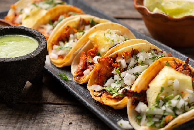 Traditional mexican pork tacos called "Al pastor" with pineapple on wooden background