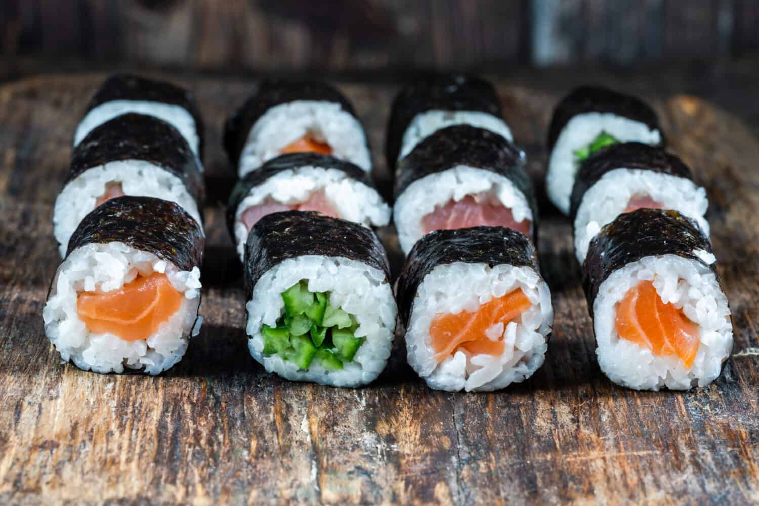 A selection of sushi rolls with salmon, tuna, cucumber and soy sauce dip.