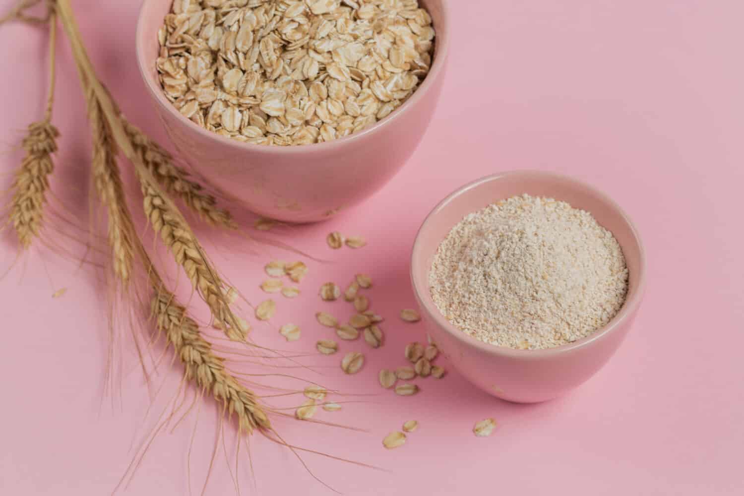 Bowl of dry oat flakes with oatmeal and ears of wheat on light background. Healthy skin, facial and body care. SPA and sauna concept.