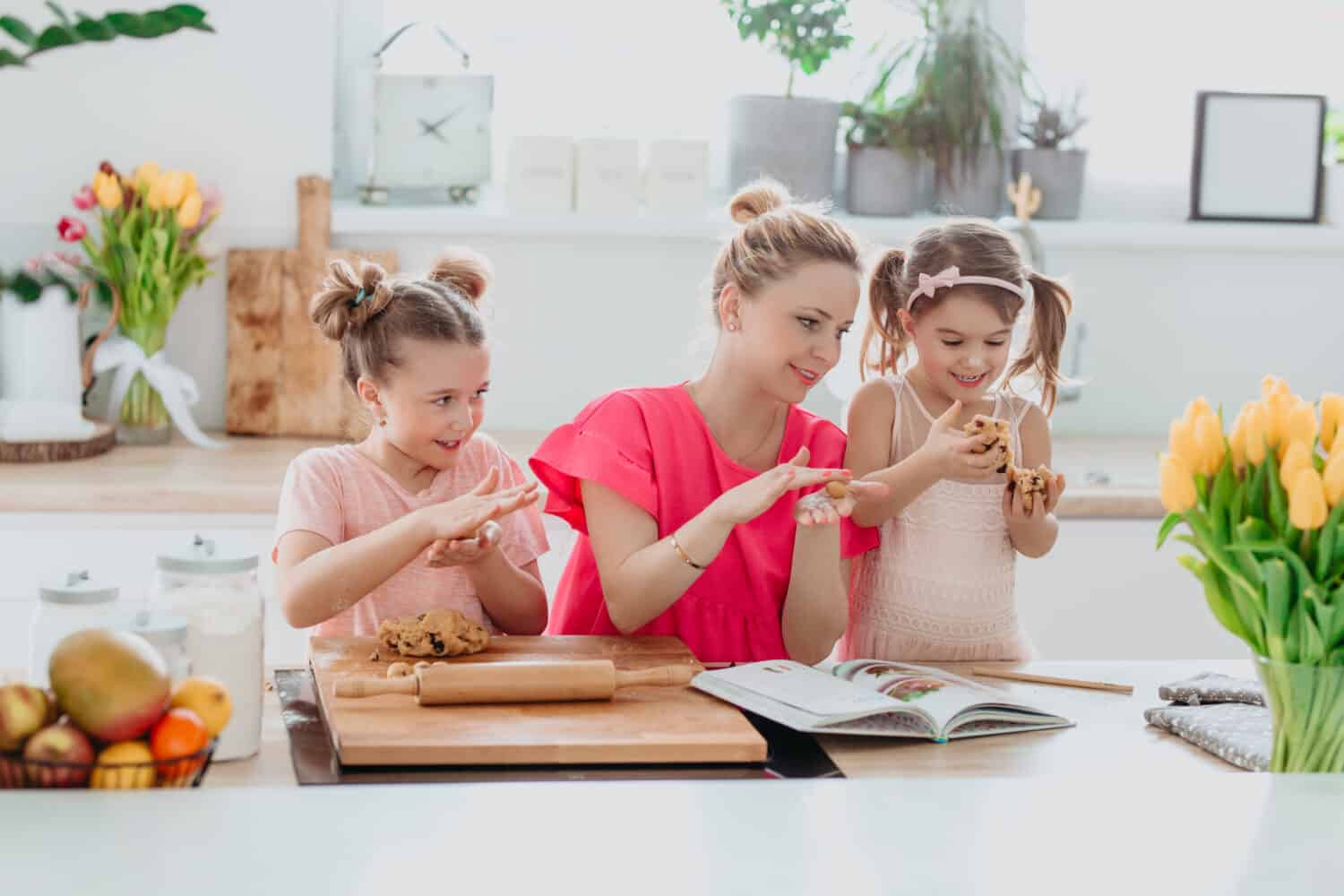 Home kitchen activities - Woman and kids baking cookies, smiling, laughing, having fun. 