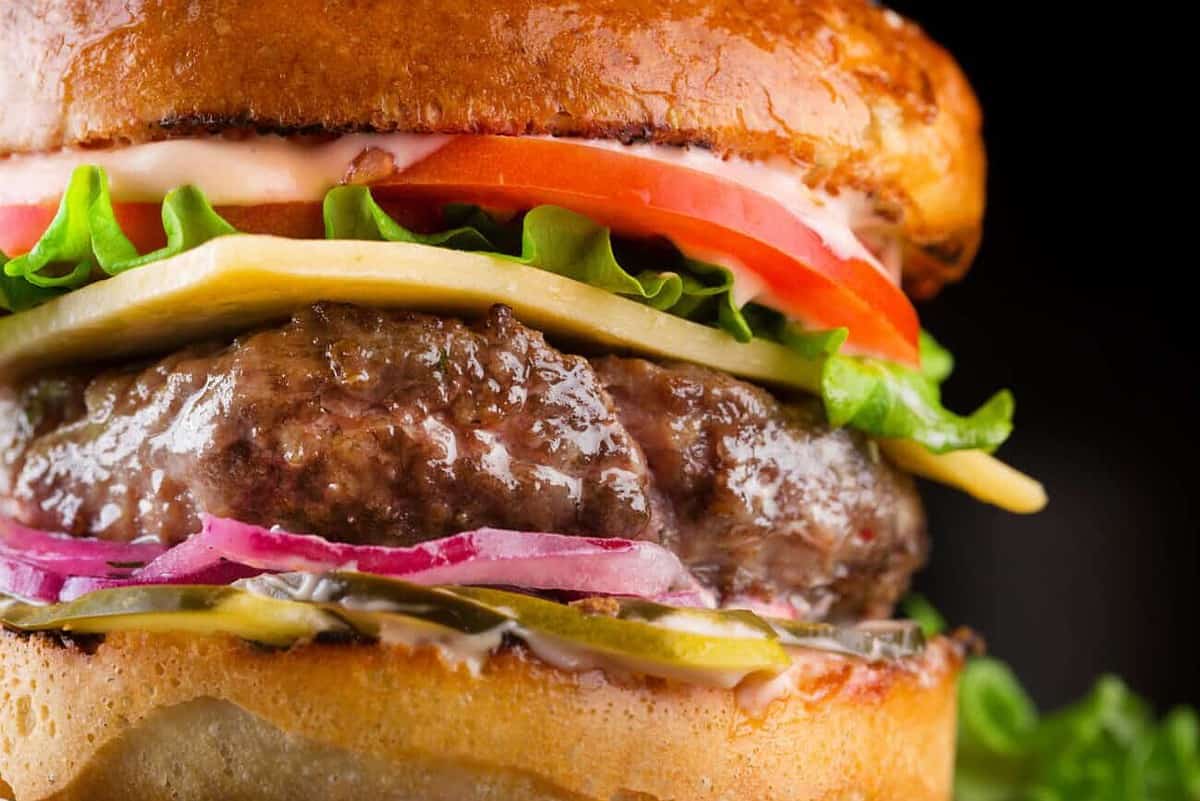 Close-up Tasty burger with beef, tomato, pickled, onion, lettuce and sauce