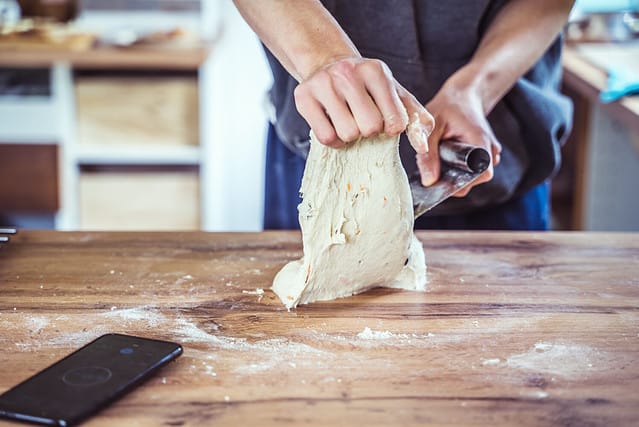 Young baker preparing artisan sourdough bread dough. Baker kneading a dough