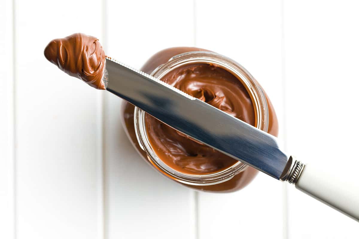 chocolate spread with knife on white table