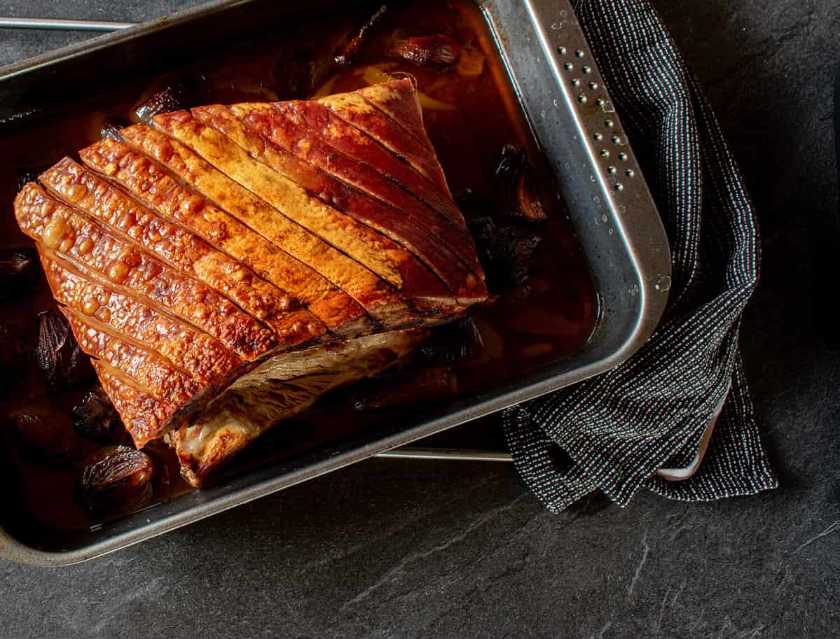 Overhead view of roasted pork belly with crust on a baking tray