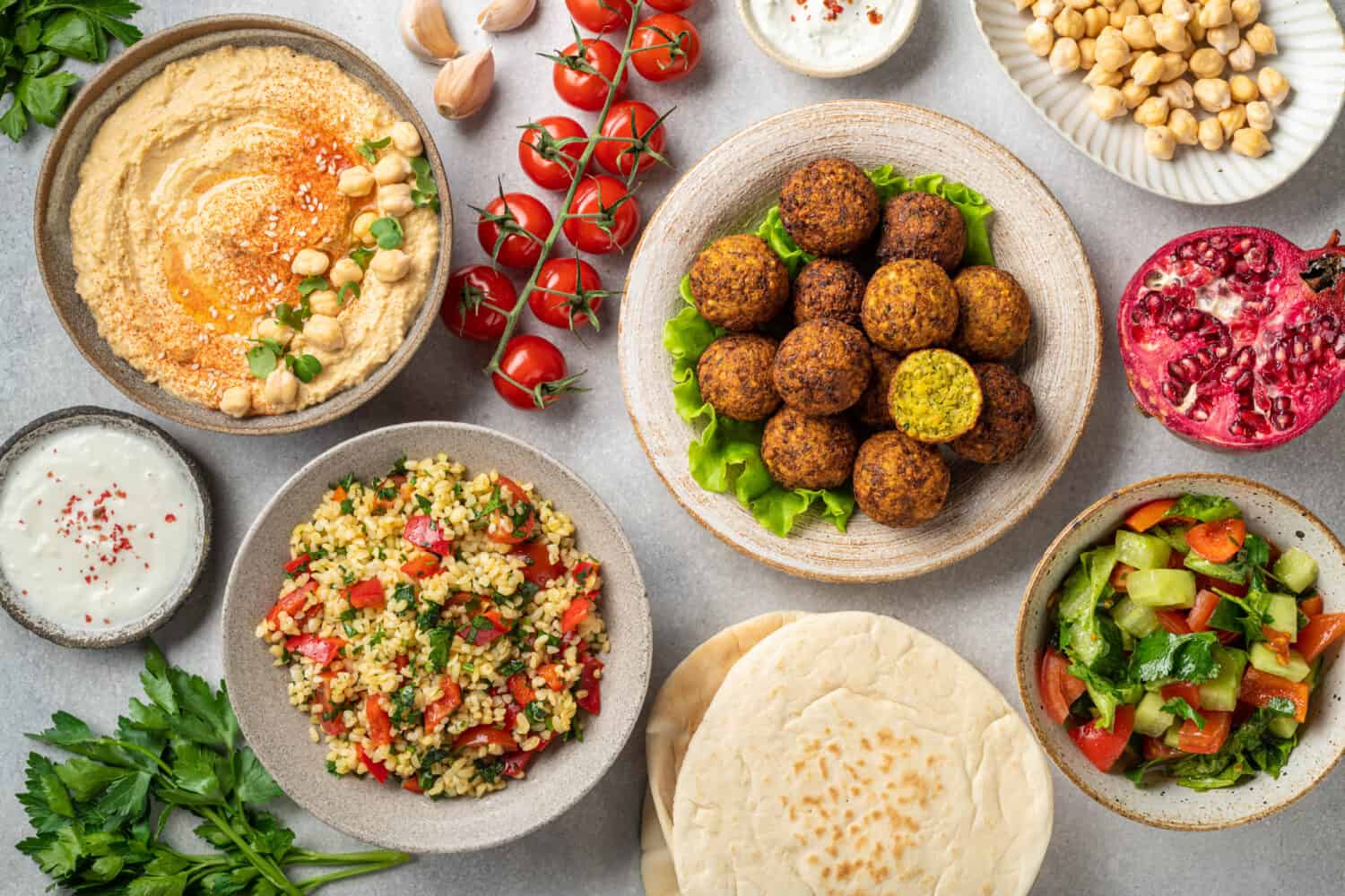 Middle eastern or arabic cuisines, falafel, hummus, tabouleh, pita and vegetables on a concrete background, view from above