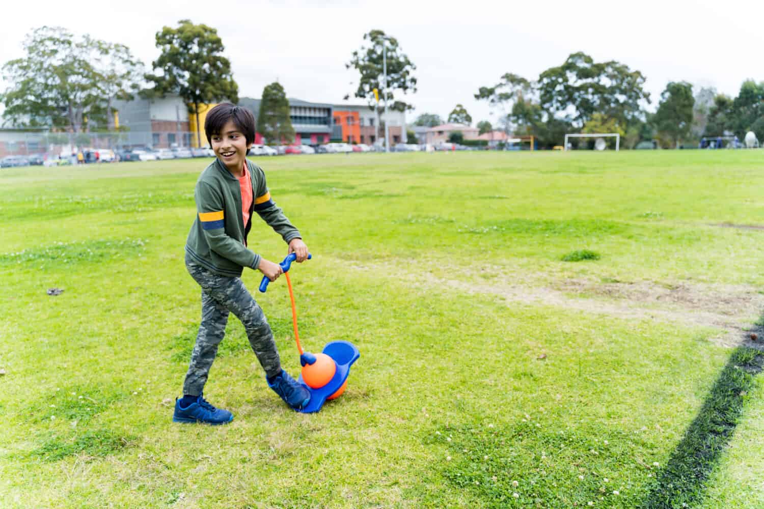 Indian kid playing with pogo toy at park in Australia. Happy young boy playing outdoors.