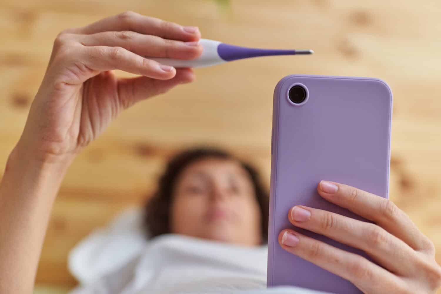 Close up of a woman's hands taking her basal temperature