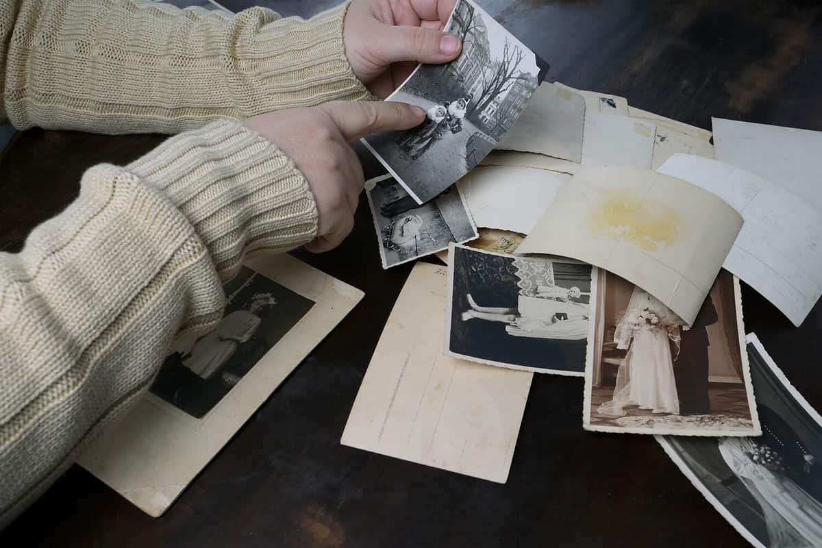 female hands fingering old photos, vintage monochrome photographs 1950, concept of genealogy, memory of ancestors, family tree, nostalgia, childhood, remembering