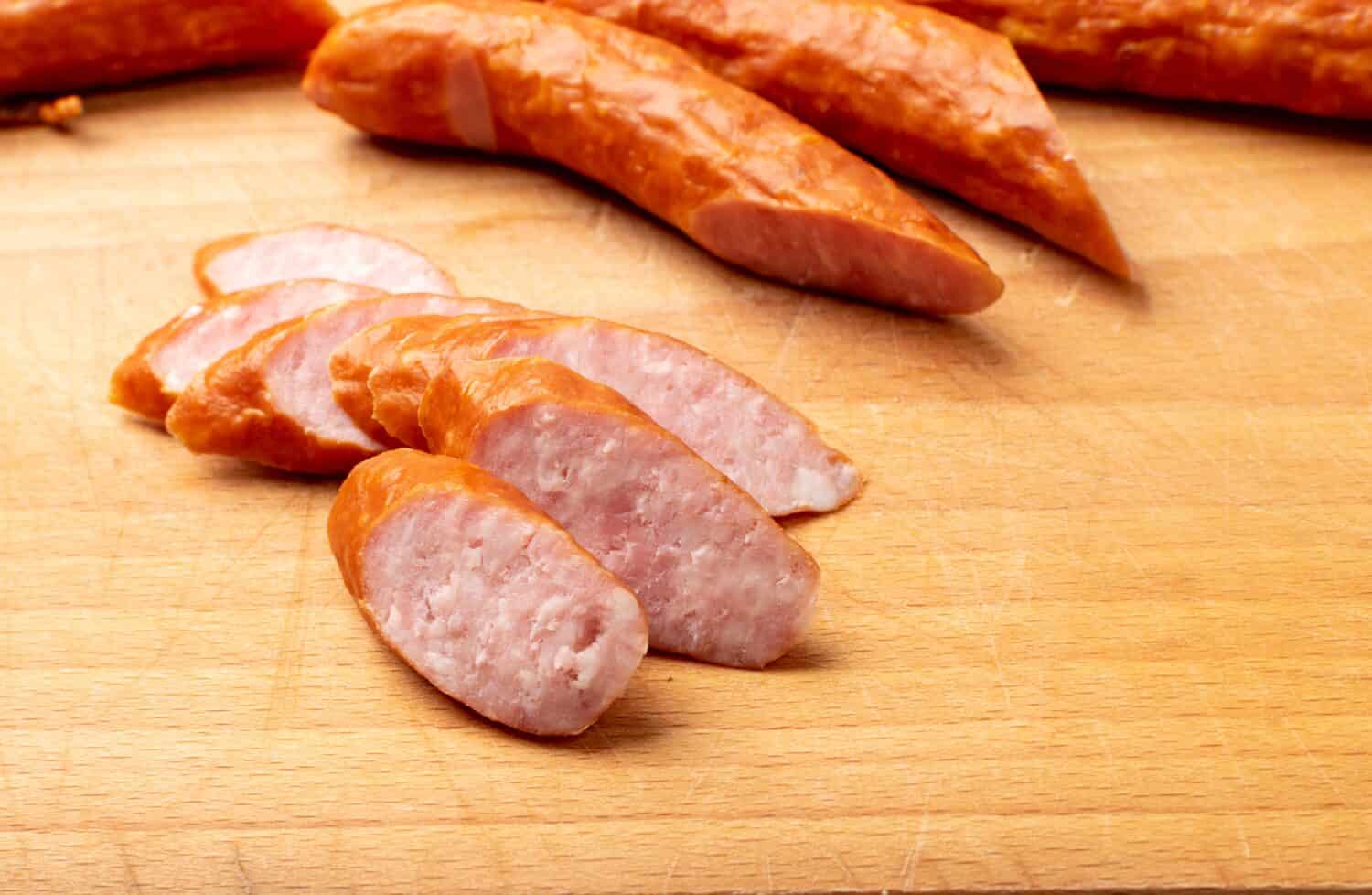 Smoked sausage cut. Hunting salami slices, chorizo pieces, wurst, poland kielbasa, grilled frankfurt sausage, longaniza on wood background