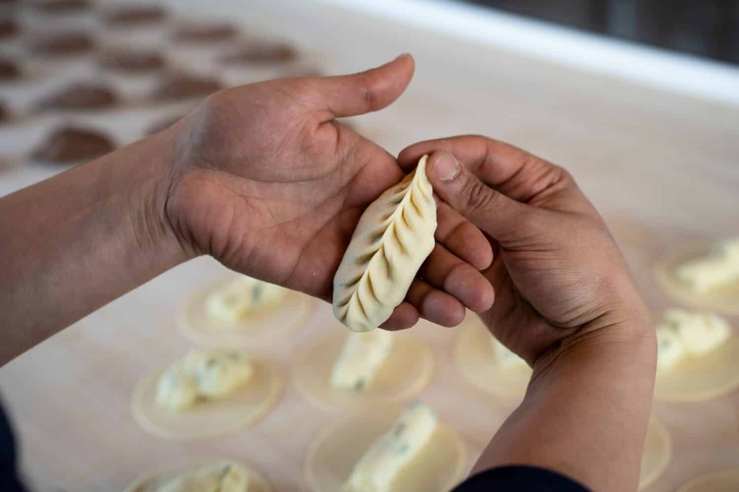 Close-up of female hands showing fresh homemade culurgiones pasta. Italian typical filled pasta from Sardinia region