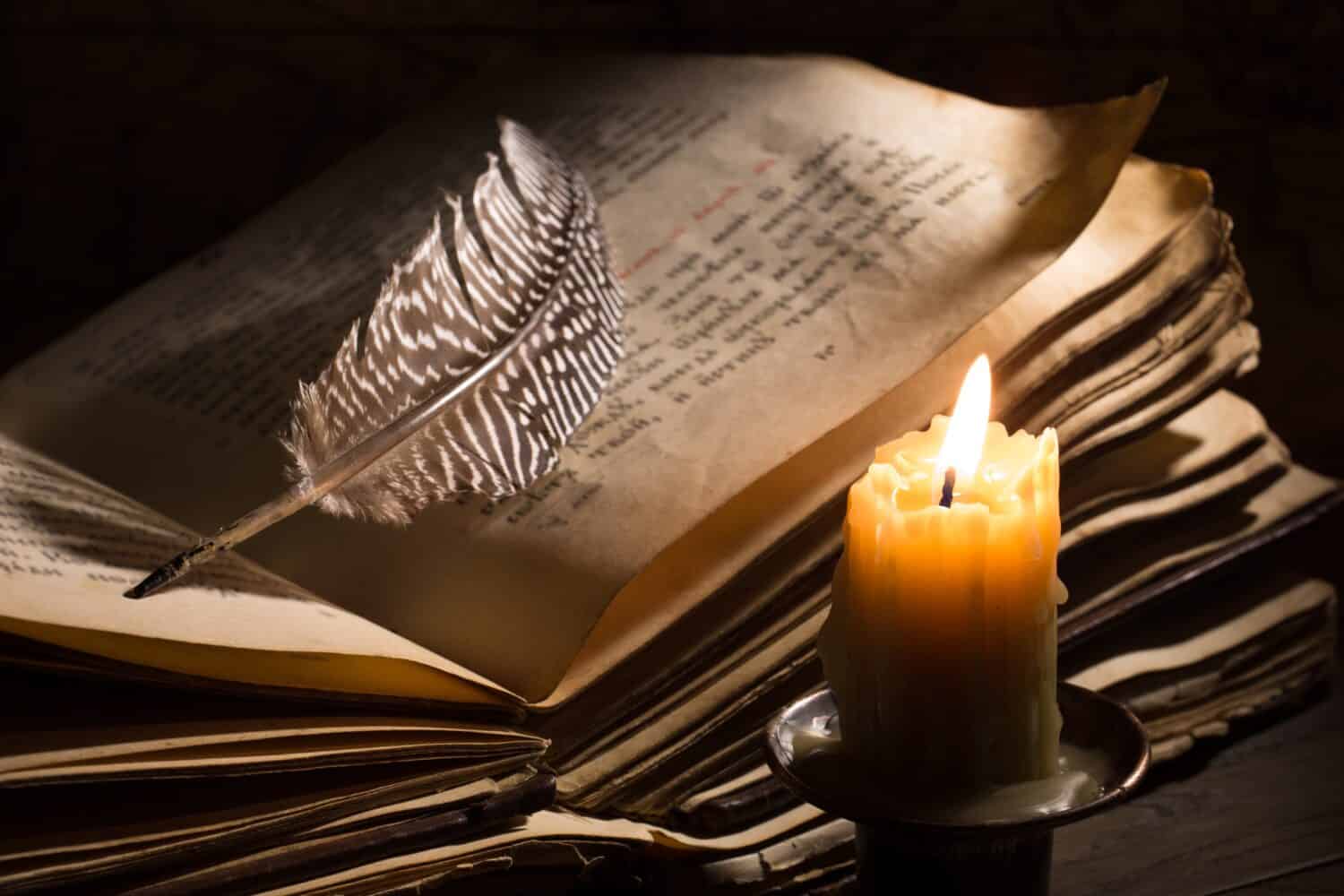Lighting candle near a medieval book. Vintage still life with open old book.