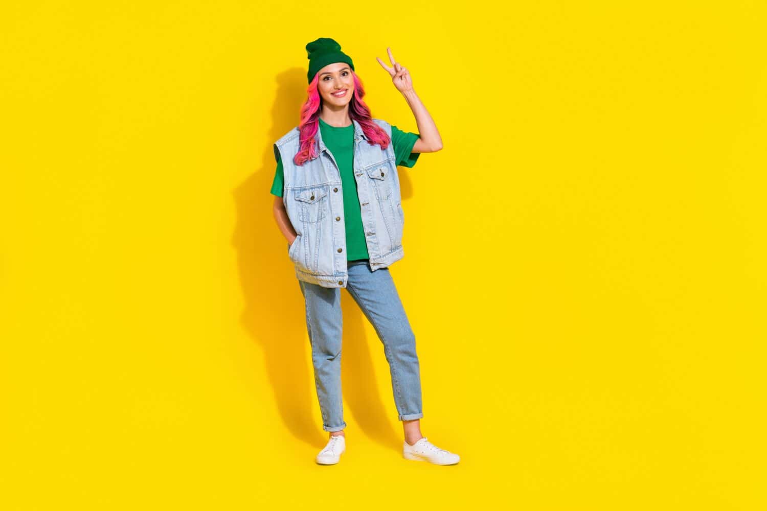 Full length photo of adorable sweet lady wear jeans waistcoat smiling showing v-sign isolated yellow color background