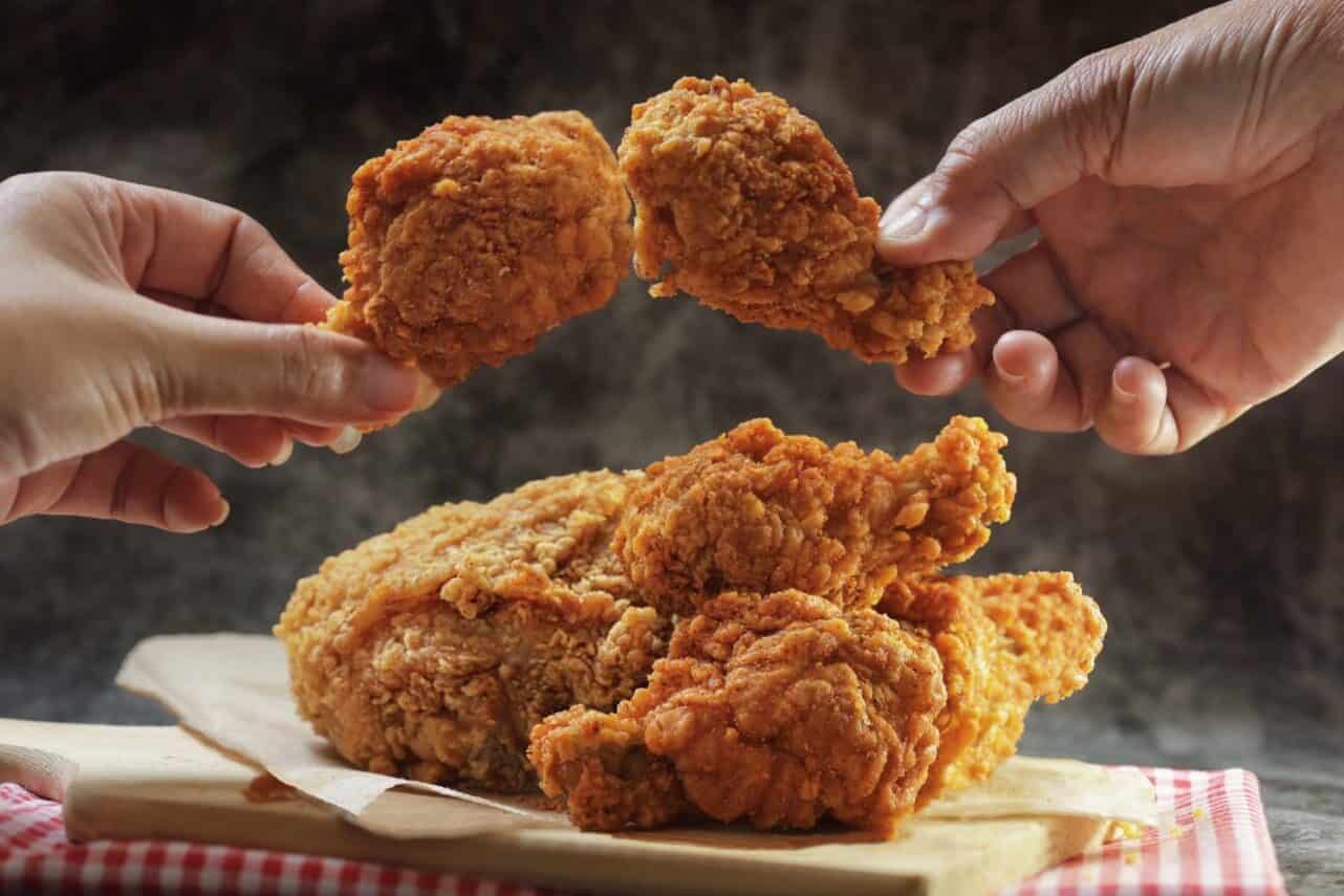 Woman hand taking the fried chicken wings by hands over dark background with copy space.