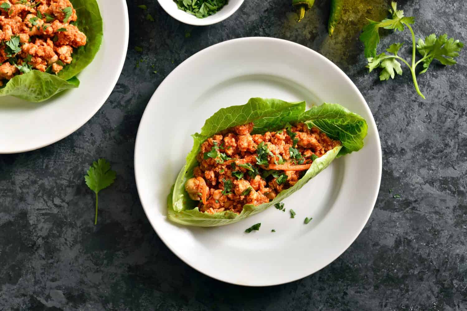 Asian minced meat lettuce wraps over dark stone background. Top view, flat lay