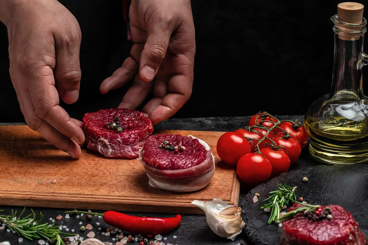 Beef medallions wrapped in bacon with rosemary and spices, Raw beef meat steak Tenderloin fillet on a cutting board. Top view. Copy space.