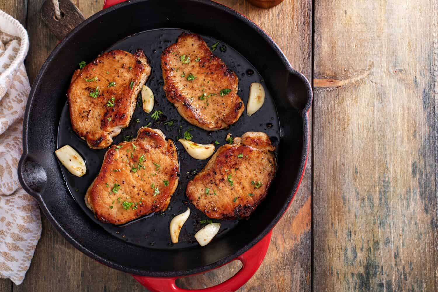 Pork chops cooked with garlic in a cast iron pan