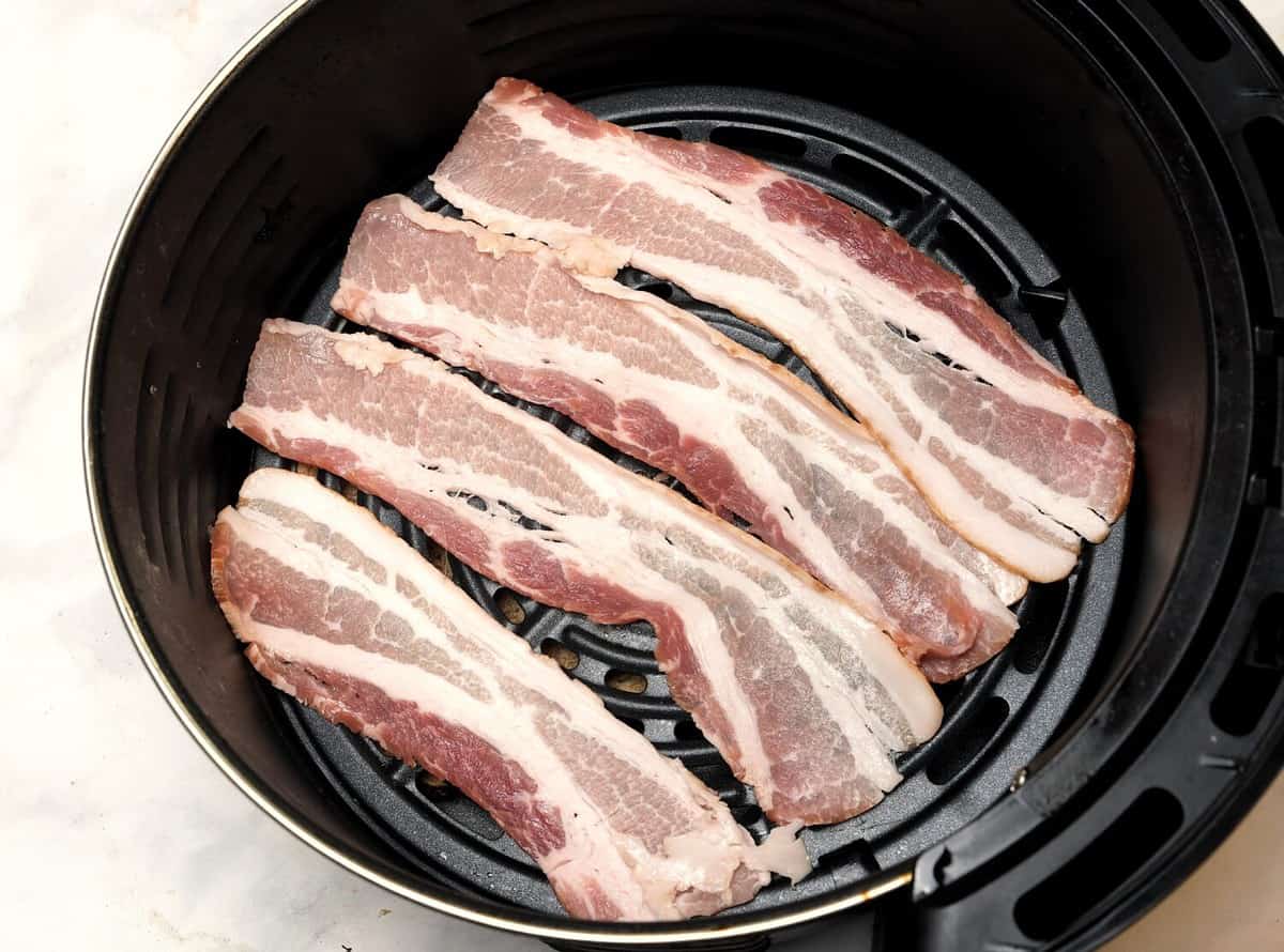 Top view of raw bacon slices in air fryer