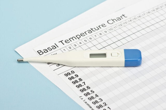 Basal temperature chart with thermometer to predict ovulation and fertility.