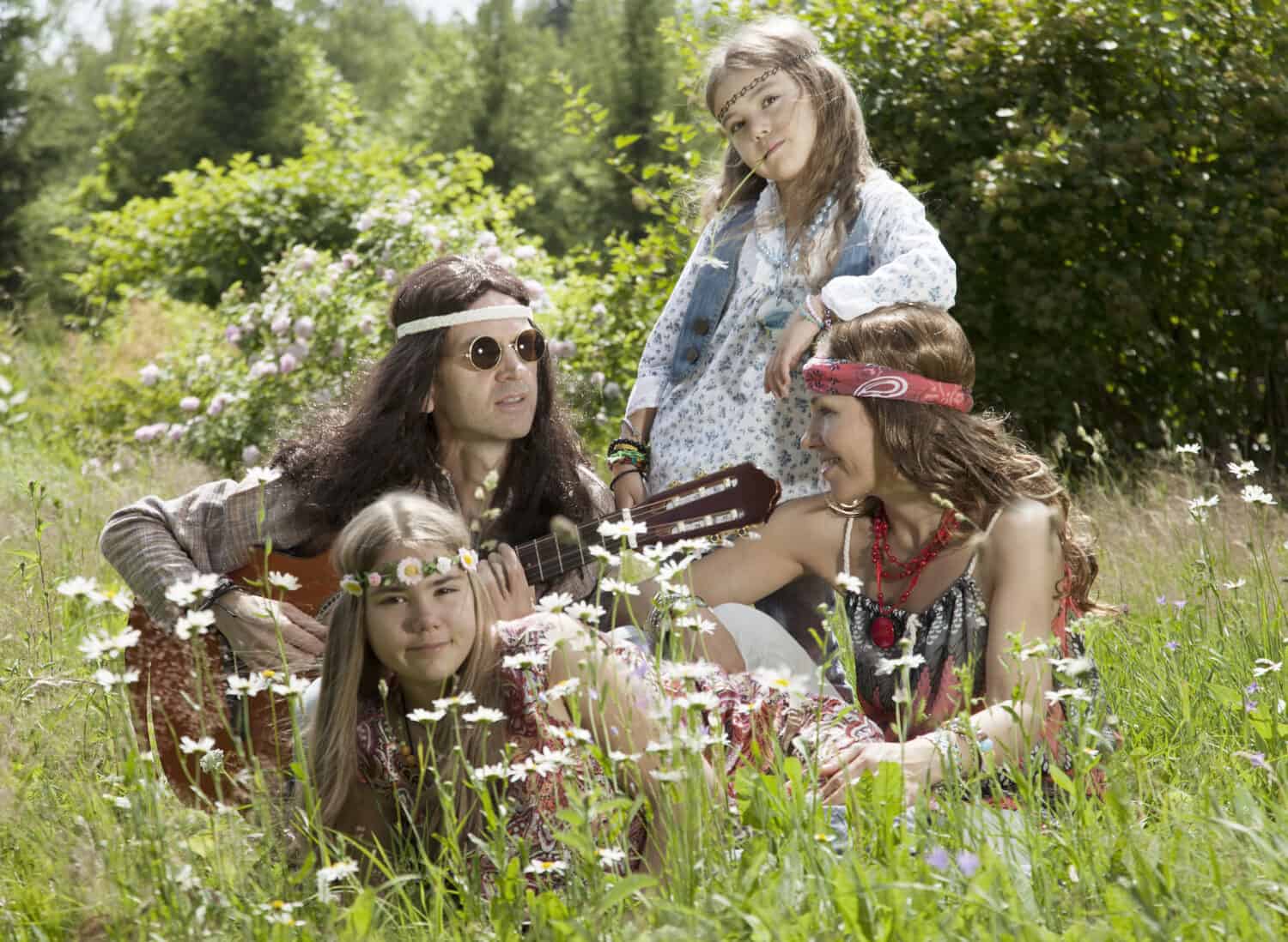 Hippie family sitting in the field and playing guitar