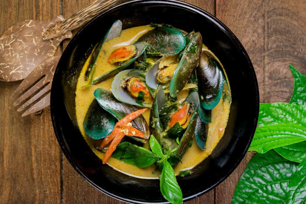 Delicious asian style curry mussels with red pepper, green onion, and coriander in a coconut broth.