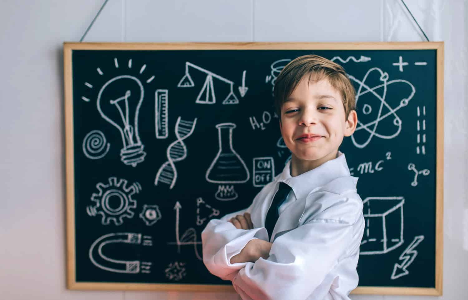 Smiling kid looking at camera in front of blackboard
