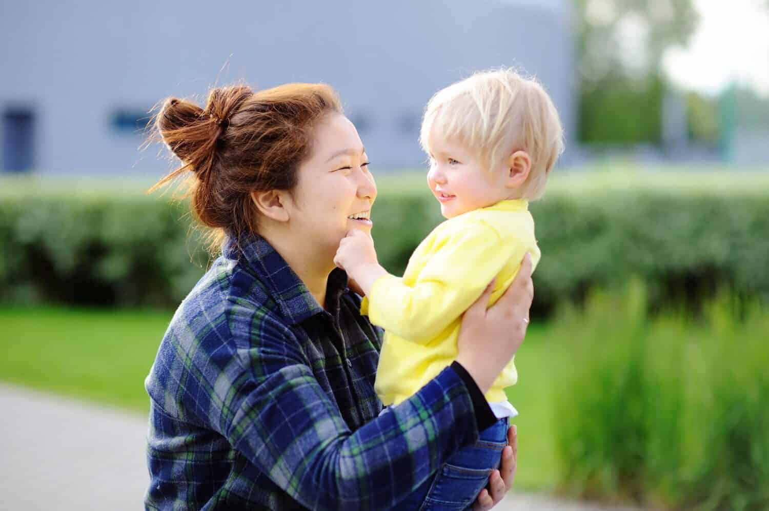 Young asian woman with cute caucasian toddler boy. Babysitting concept