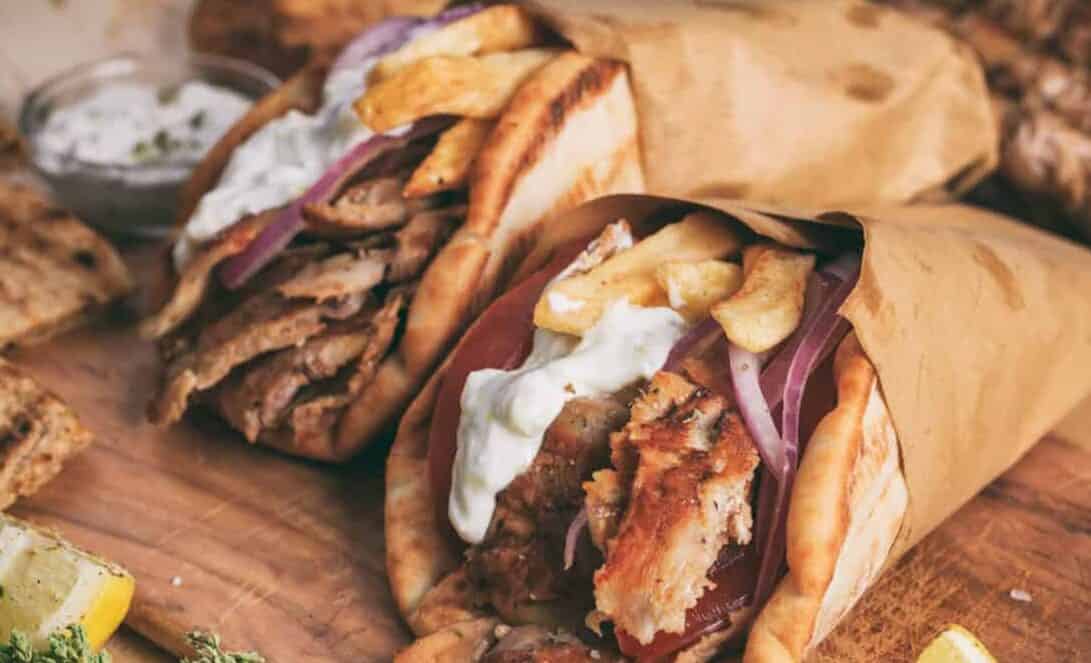 Greek gyros wrapped in pita breads on a wooden background