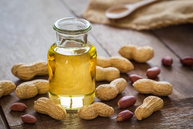 Peanut oil in glass bottle and peanuts on wooden table