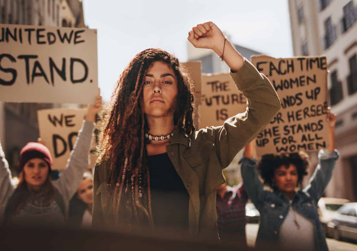 Woman leading a group of demonstrators on road. Group of female protesting for equality and women empowerment.