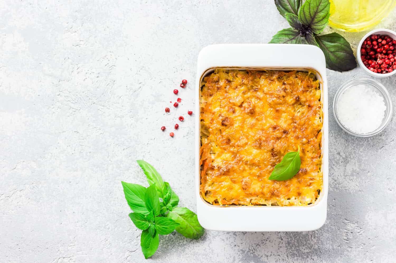 Cheesy stuffed cabbage casserole on concrete background. Top view, space for text.