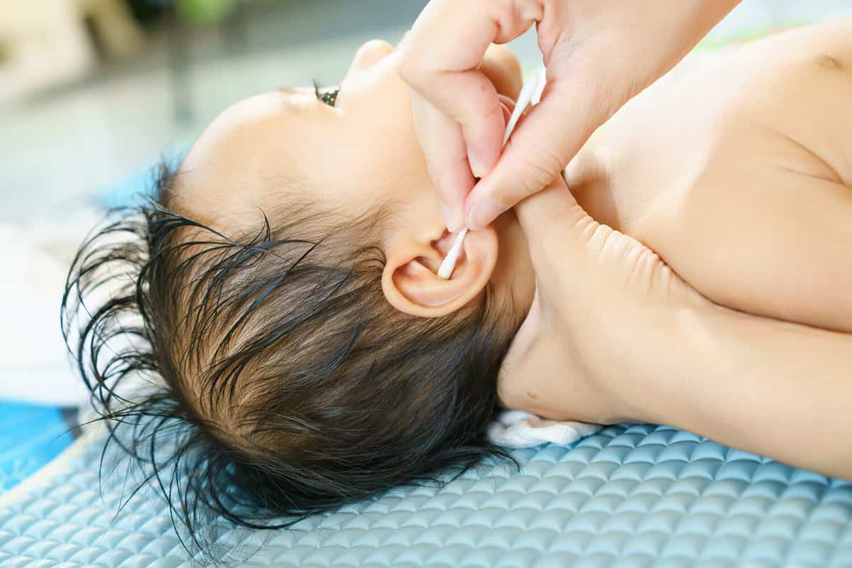 mother is cleaning the baby's ear by cotton buds.Asian family,living lifestyle indoors.hygiene,Selective focus,noise