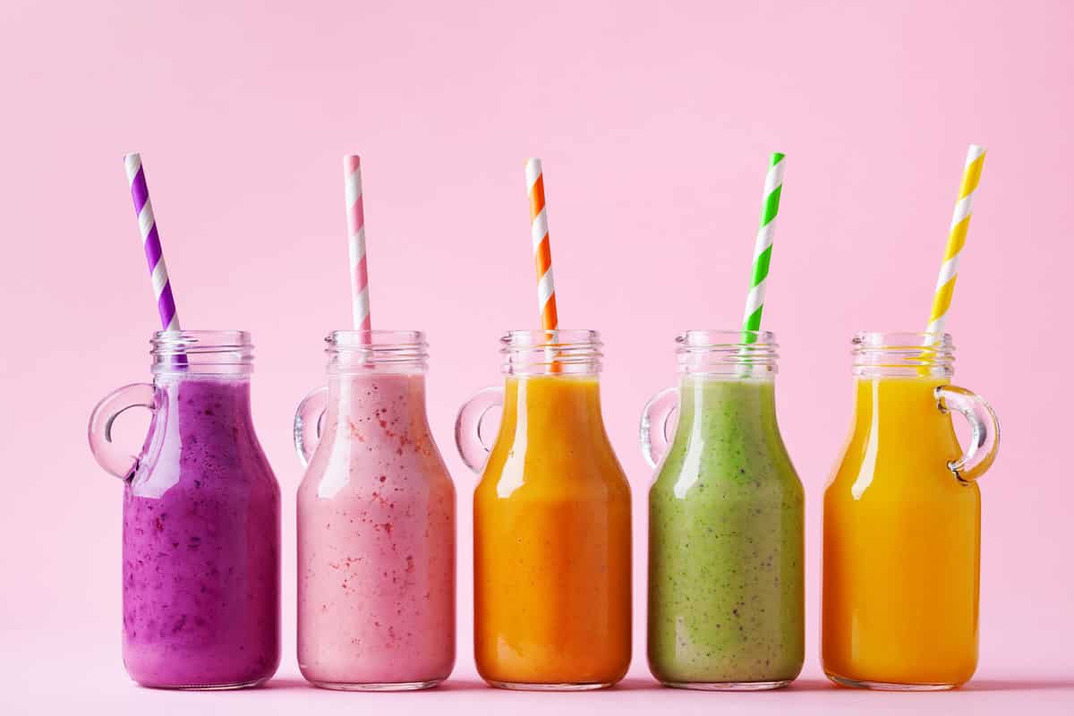Summer colorful fruit smoothies in jars on pink background. Healthy, detox and diet food concept.