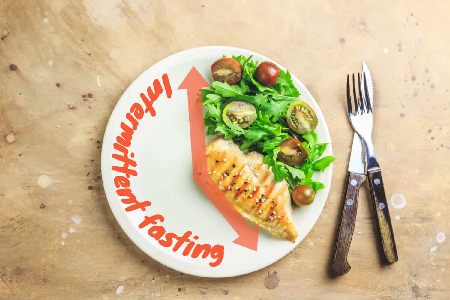 Intermittent fastin concept. One-third plate with healthy food and two-third plate is empty. Chicken fillet, arugula and tomatoes on a plate. Top view. Flat lay