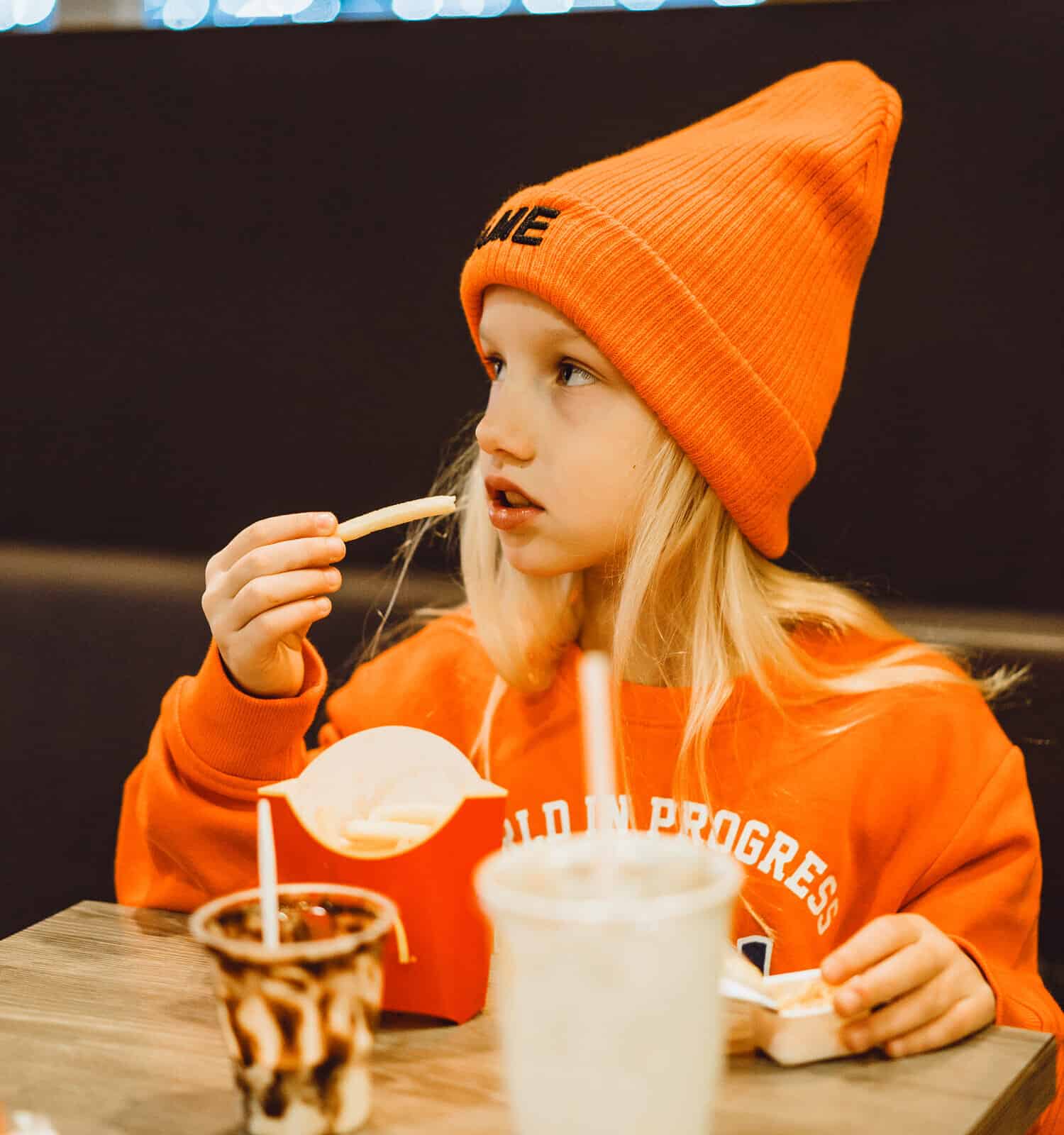 children at mcdonald's. Little girl eats french fries and drinks a cocktail in a cafe.