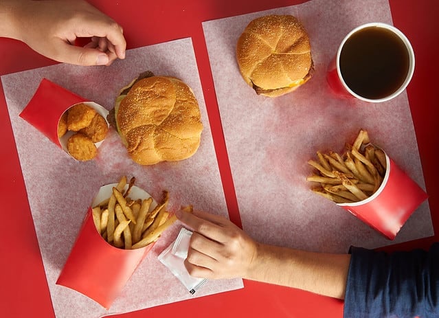 Top view of red table with wendy burgers and hands picking on food friends sharing and stealing food