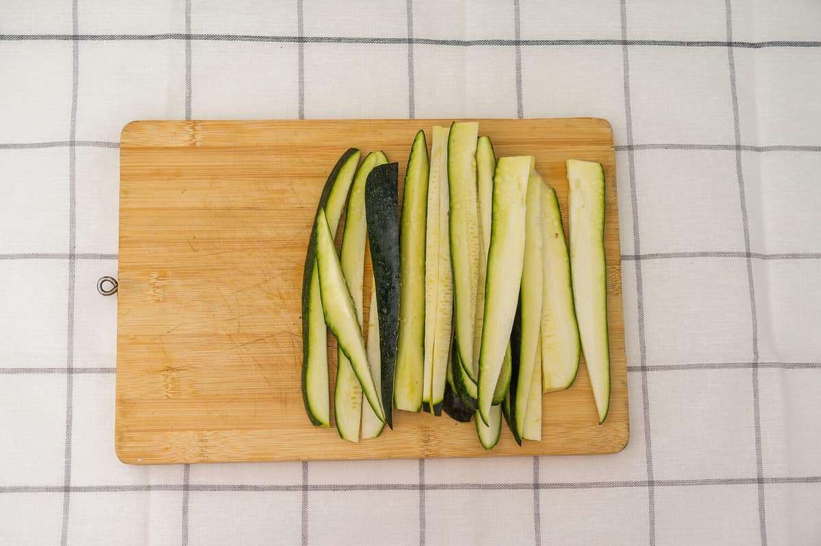 zucchini strips on a wooden cutting board.