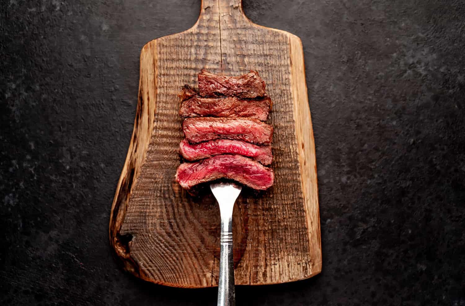 Different degrees of roasting steak on a meat fork on a stone background