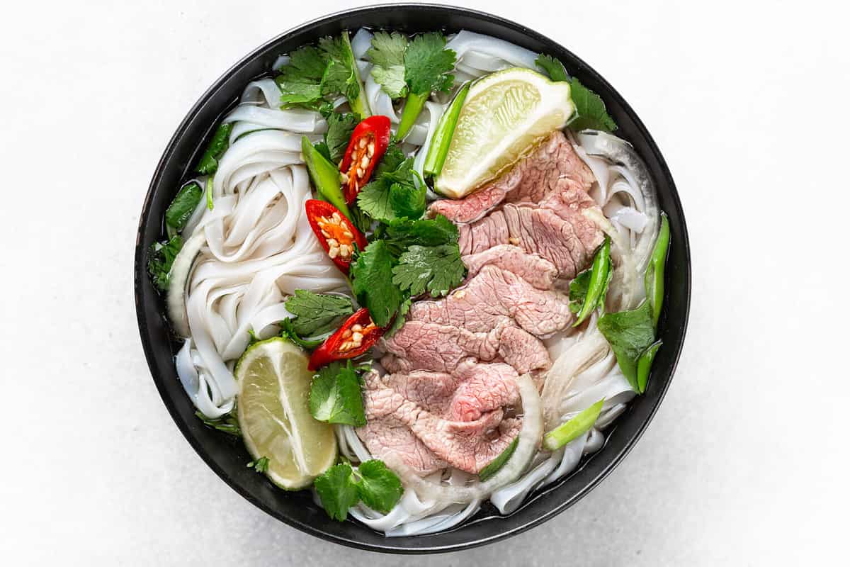 Pho Bo vietnamese soup with beef and rice noodles on a white background, top view, close-up