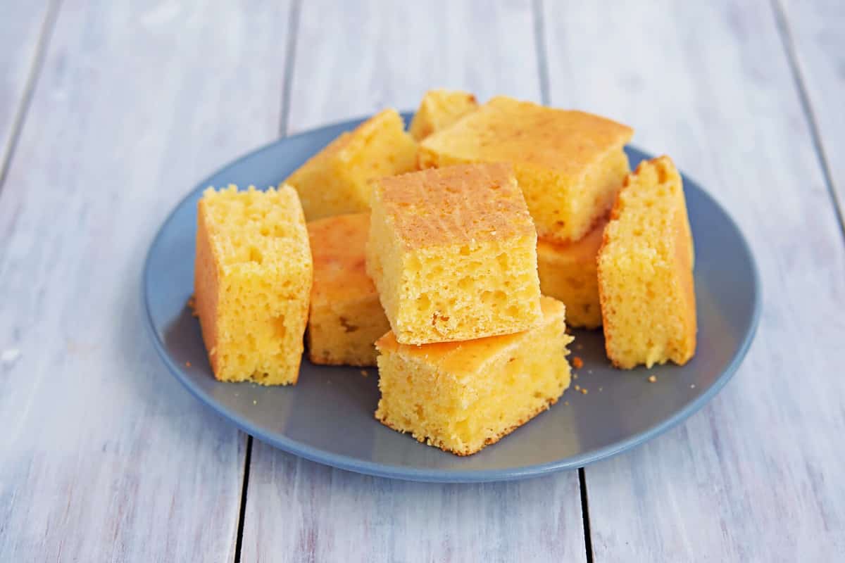 Sliced cornbread on a gray plate on a light wooden background. Corn flour recipes. American food. Copyspace.
