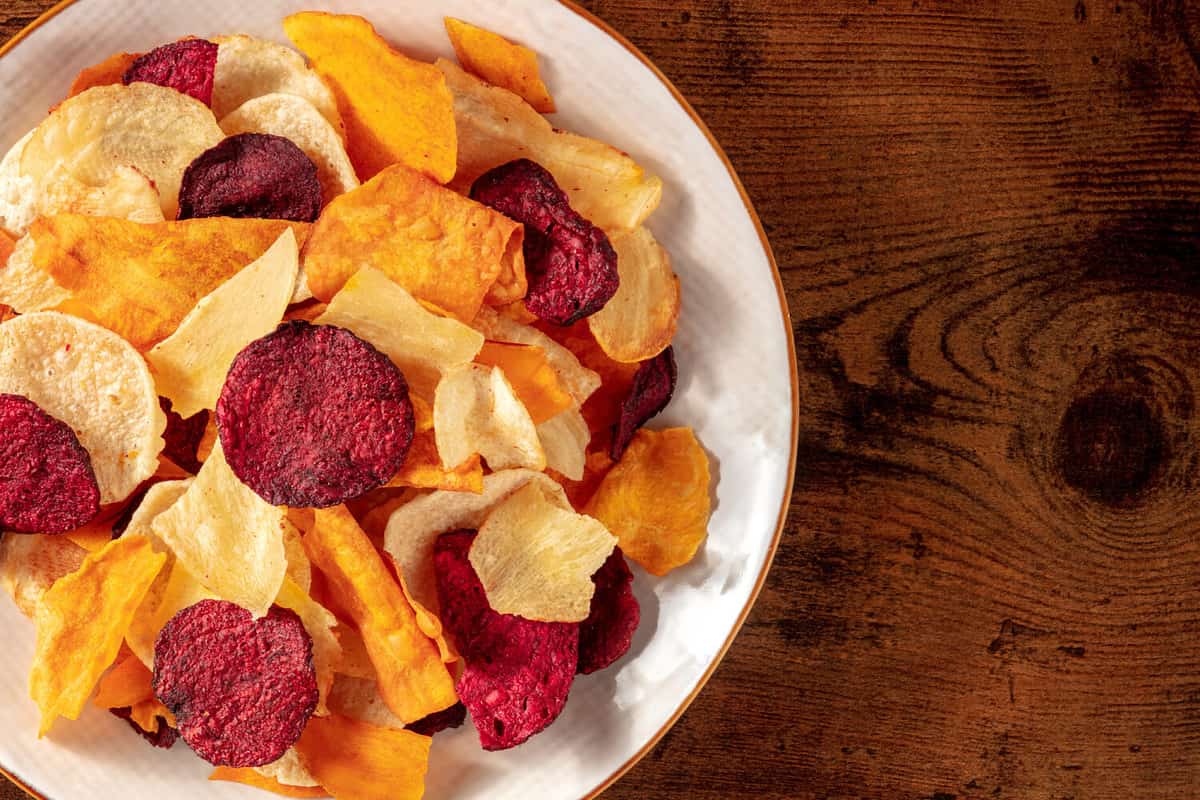 Fruit and vegetable chips, close-up with copy space on a dark rustic wooden background
