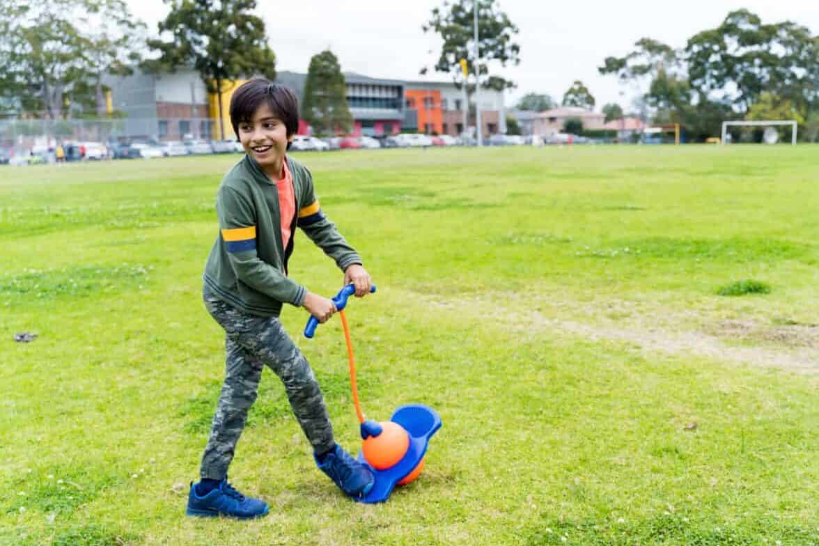 Indian kid playing with pogo toy at park in Australia. Happy young boy playing outdoors.