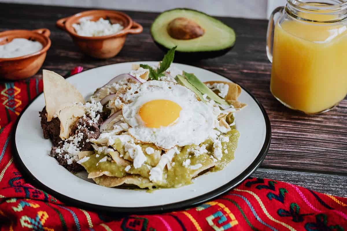 mexican chilaquiles with fried egg, chicken and spicy green sauce traditional breakfast in Mexico