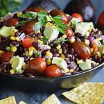 Homemade Mexican black bean and corn salad or Texas caviar bean dip lime dressing, Served with tortilla chips and fresh ingredients. Blurred background.