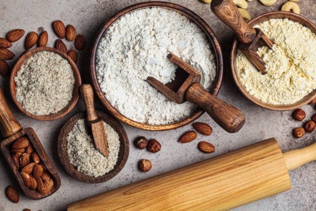 Different types of nut flour - almond, hazelnut and cashew, top view, dark background. Keto diet and gluten-free concept.