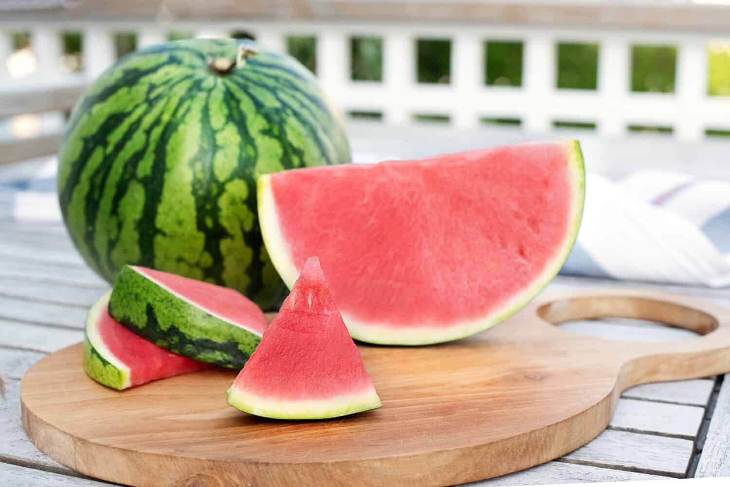 Summer berry, seedless watermelon and slices on a table on wooden terrace.