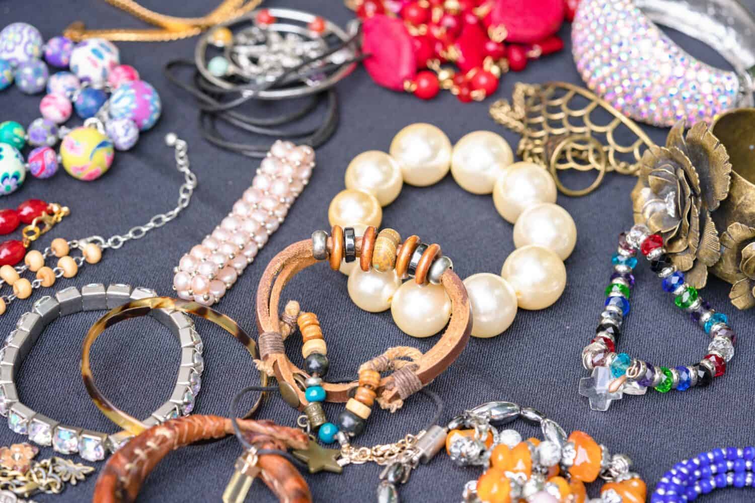 Many vintage old-fashioned jewelry at flea market stall or car boot sale. Retro style bracelets and necklaces. Vintage goods for sale. Garage sale concept. Selective focus
