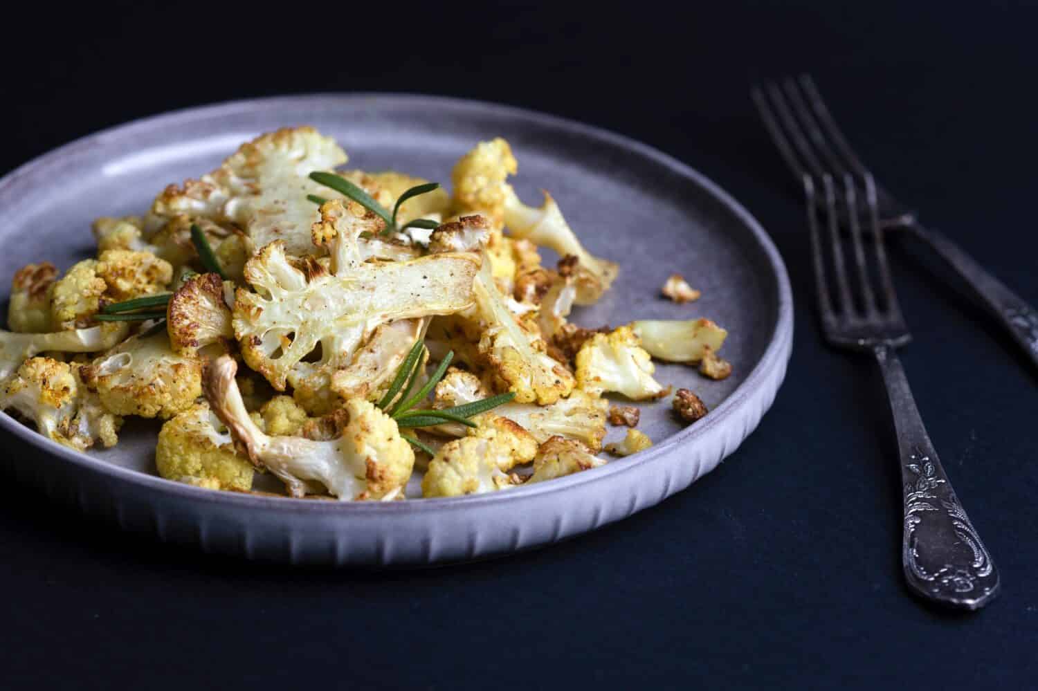 baked cauliflower on a black background. french cuisine